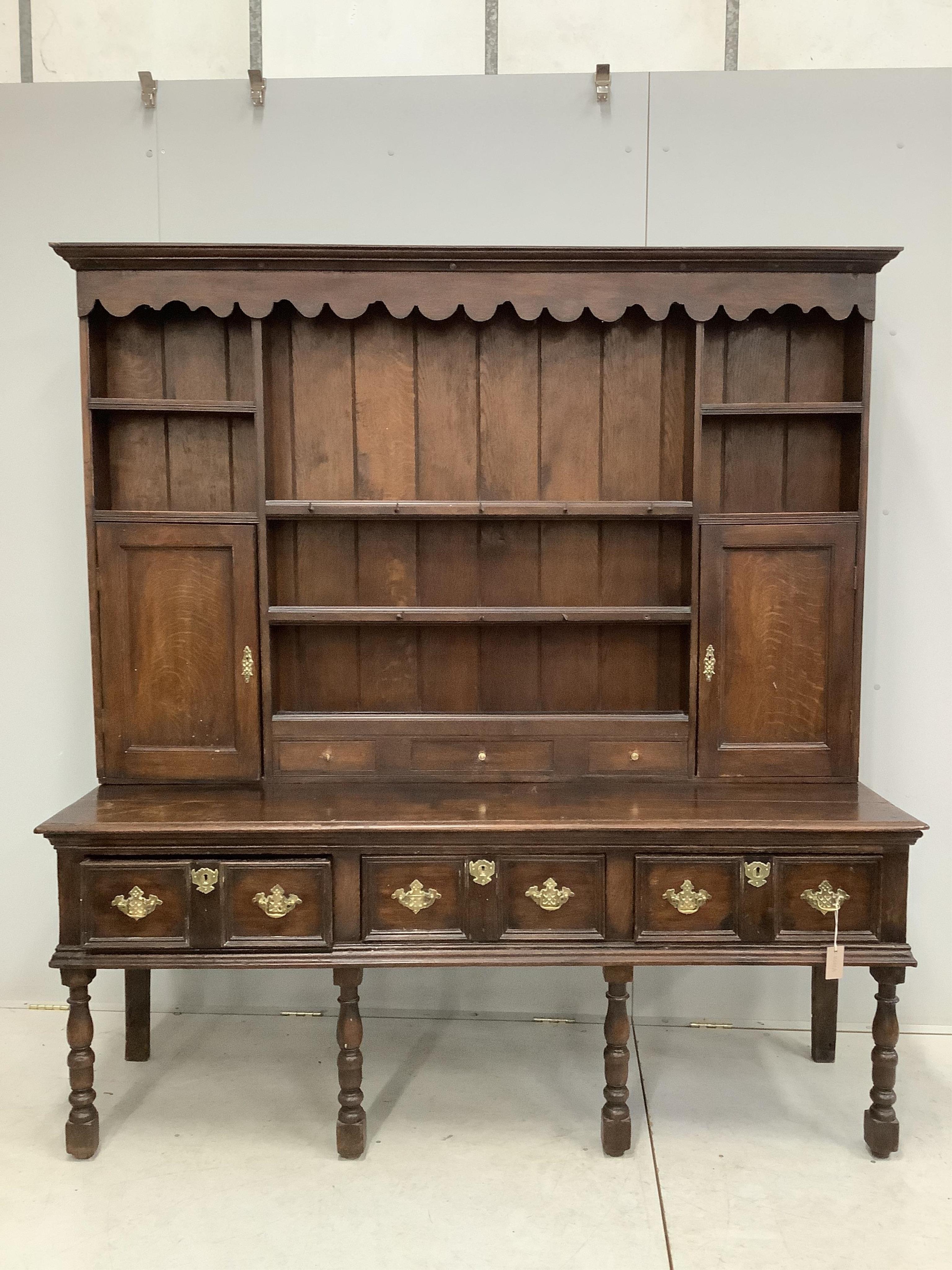 An 18th century style oak dresser with boarded rack, width 178cm, depth 52cm, height 190cm. Condition - fair, surfaces scratched